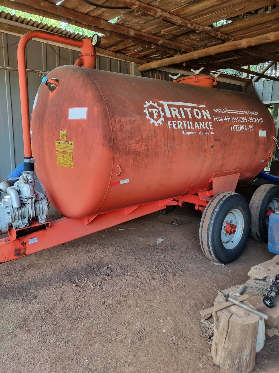 Distribuidor de fertilizantes líquidos Triton Fertilance da Associação, com tanque e bomba, guardado no galpão